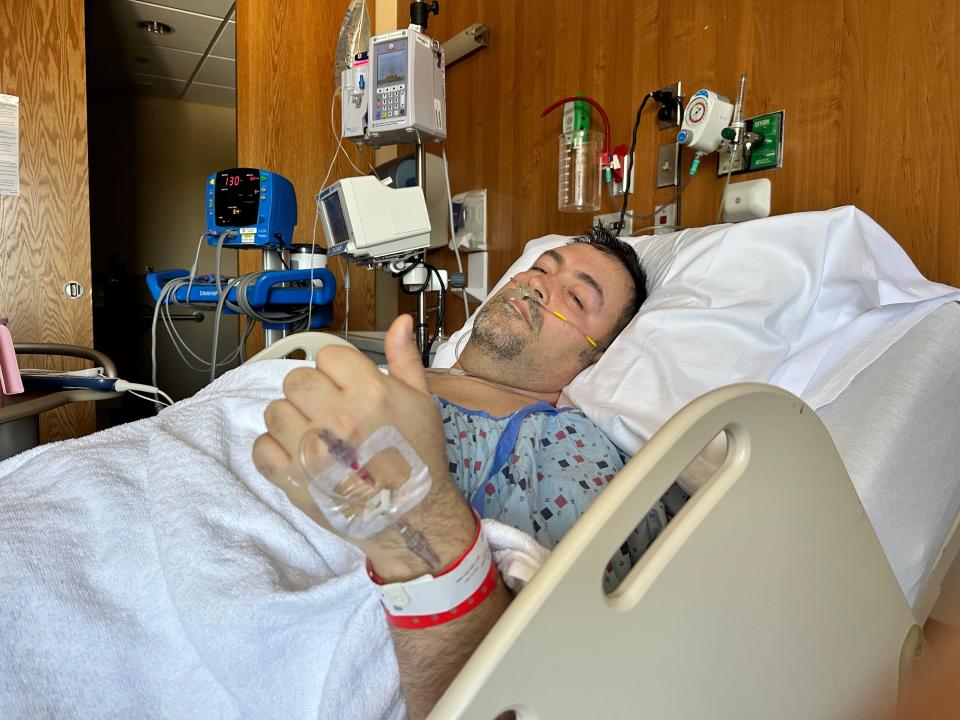A man giving the thumbs up in a hospital bed after surgery.