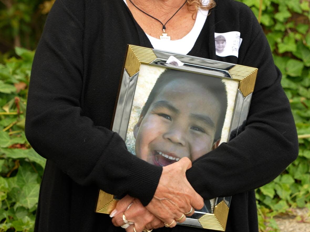 A woman holds a photo of Dontay Lucas outside the Port Alberni courthouse on Thursday, May 16, 2024, ahead of sentencing in the Hesquiat boy's manslaughter case.  (Claire Palmer/CBC - image credit)