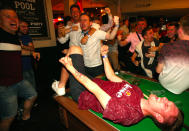 <p>An England supporter writhes with delight on a pool table in the Lord Raglan pub in London.<br>(Picture: PA) </p>