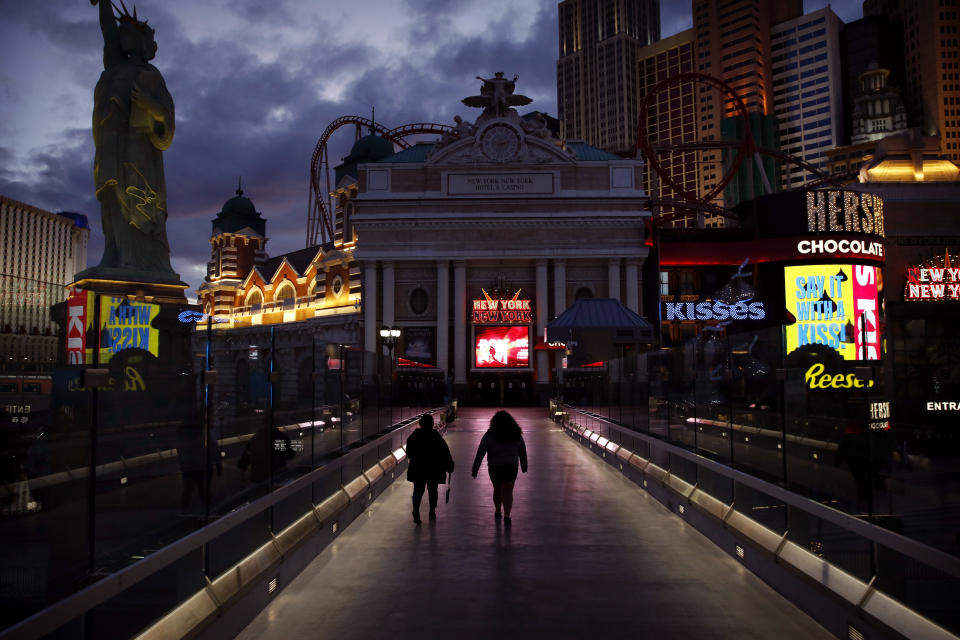 People walk along the Las Vegas Strip devoid of the usual crowds after casinos were ordered to shut down due to the coronavirus outbreak, March 18, 2020, in Las Vegas. (AP Photo/John Locher)