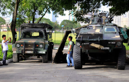 A man use a mobile phone to take pictures of his friend beside an Armoured Personnel Carrier (APC) parked near the venue of the 50th ASEAN Foreign Ministers meeting in Pasay city, metro Manila, Philippines August 4, 2017. REUTERS/Romeo Ranoco