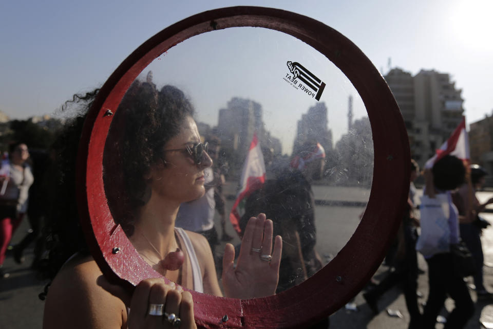 An anti-government protester plays a tambourine during a protest in Beirut, Lebanon, Tuesday, Oct. 22, 2019. Prime Minister Saad Hariri briefed western and Arab ambassadors Tuesday of a reform plan approved by the Cabinet that Lebanon hopes would increase foreign investments to help its struggling economy amid wide skepticism by the public who continued in their protests for the sixth day. (AP Photo/Hassan Ammar)