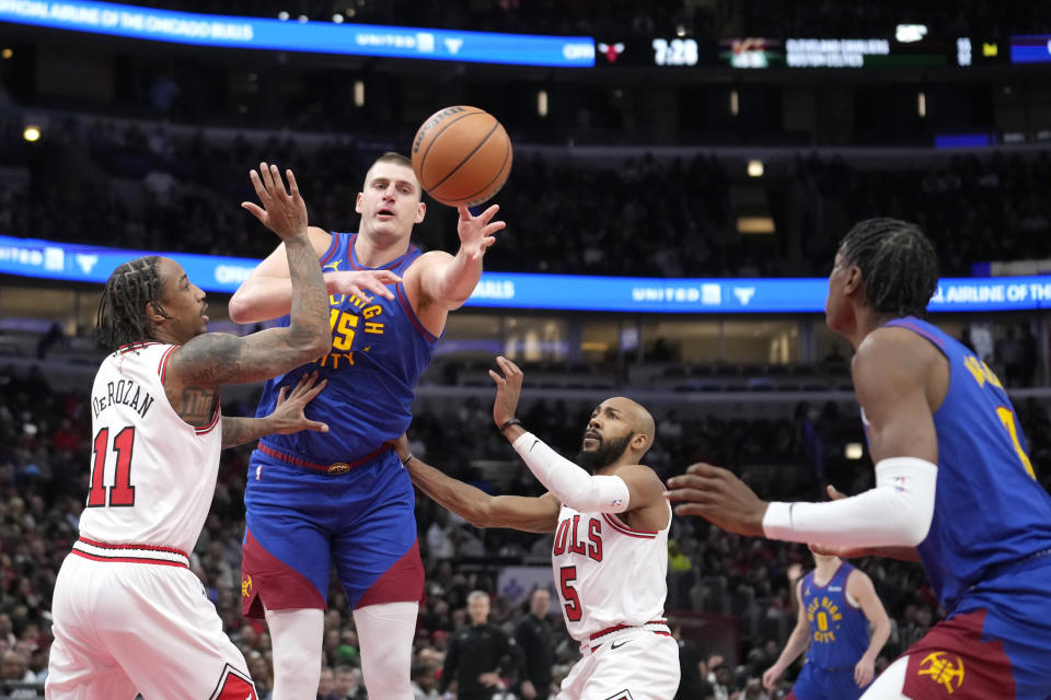 Denver Nuggets center Nikola Jokic passes to Peyton Watson as Chicago Bulls forward DeMar DeRozan (11) and Jevon Carter defend during the first half of an NBA basketball game Tuesday, Dec. 12, 2023, in Chicago. (AP Photo/Charles Rex Arbogast)