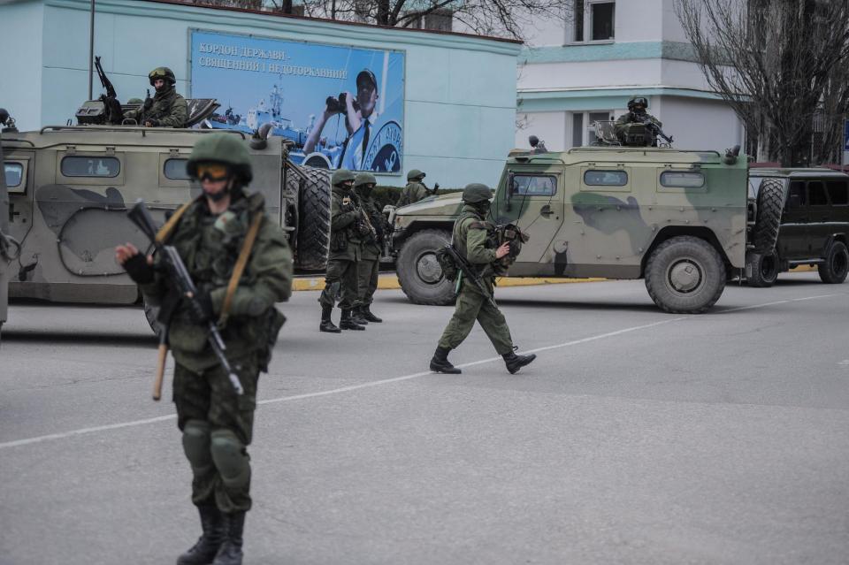 Troops in unmarked uniforms stand guard as they take control the Coast Guard offices in Balaklava on the outskirts of Sevastopol, Ukraine, Saturday, March 1, 2014. An emblem on one of the vehicles and their number plates identify them as belonging to the Russian military. Ukrainian officials have accused Russia of sending new troops into Crimea, a strategic Russia-speaking region that hosts a major Russian navy base. (AP Photo/Andrew Lubimov)