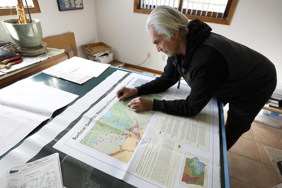 In this Nov. 1, 2018, photo, Gordon Garrison looks over geological maps of land surrounding his farm, in Estherville, Iowa. Garrison sued a nearby operation with 4,400 hogs, contending manure from its croplands fouls a creek that runs through his property and feeds the Des Moines River. (AP Photo/Charlie Neibergall)