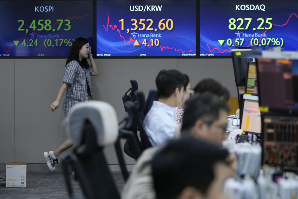 A currency trader passes by the screens showing the Korea Composite Stock Price Index (KOSPI), left, and the foreign exchange rate between U.S. dollar and South Korean won, center, at the foreign exchange dealing room of the KEB Hana Bank headquarters in Seoul, South Korea, Wednesday, Sept. 27, 2023. Shares in Asia were mostly lower on Wednesday after Wall Street’s ugly September got even worse, with benchmarks dropping back to where they were in June.(AP Photo/Ahn Young-joon)