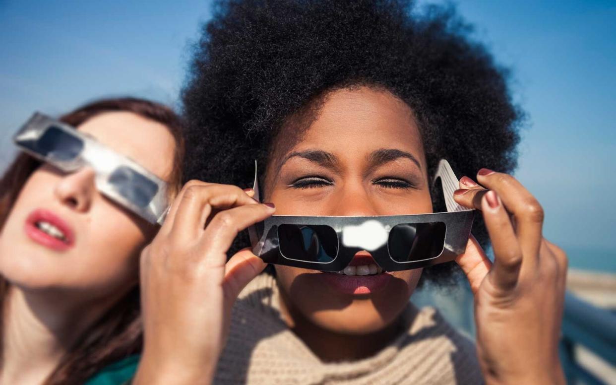 Group of female friends have fun together during a solar eclipse event.