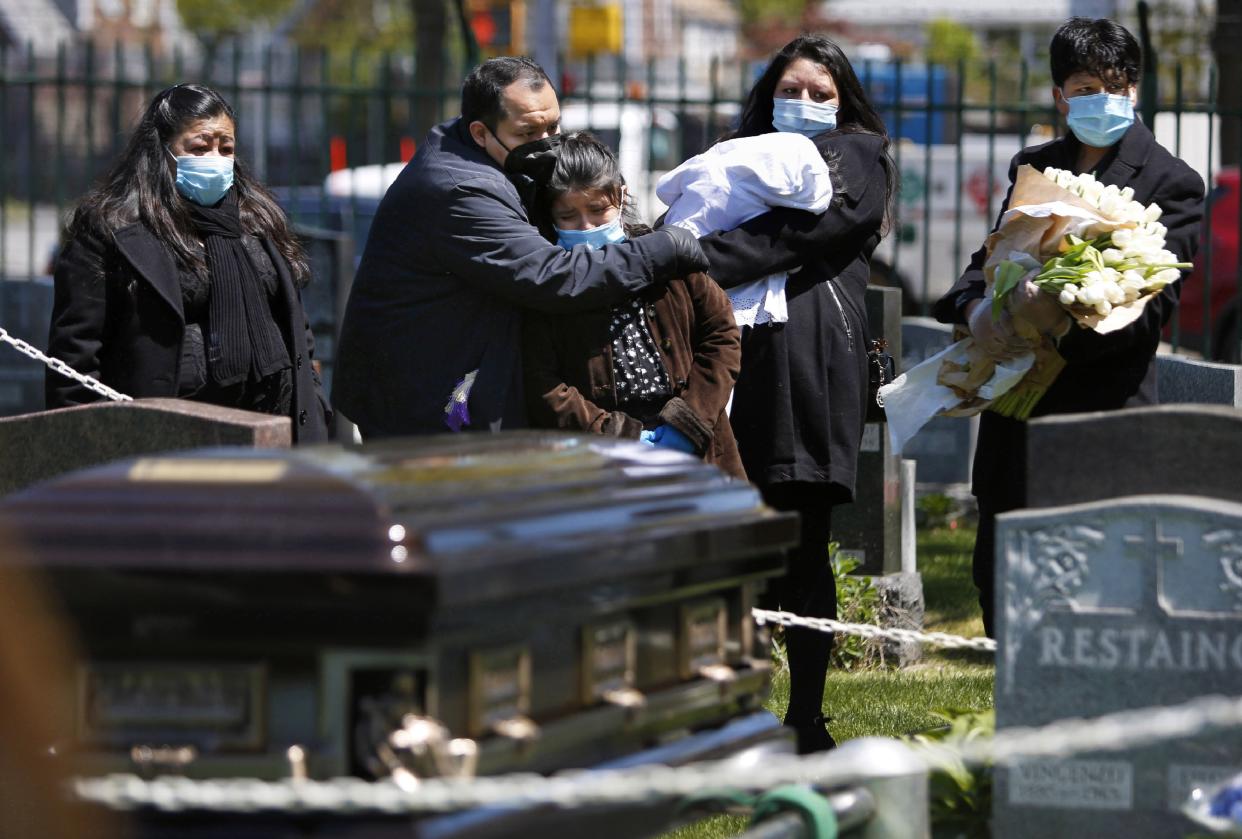 The Rev. Joseph Dutan comforts his niece, Valerie Dutan, at the funeral of his father, Manuel Dutan, at St. John's Cemetery in Queens.