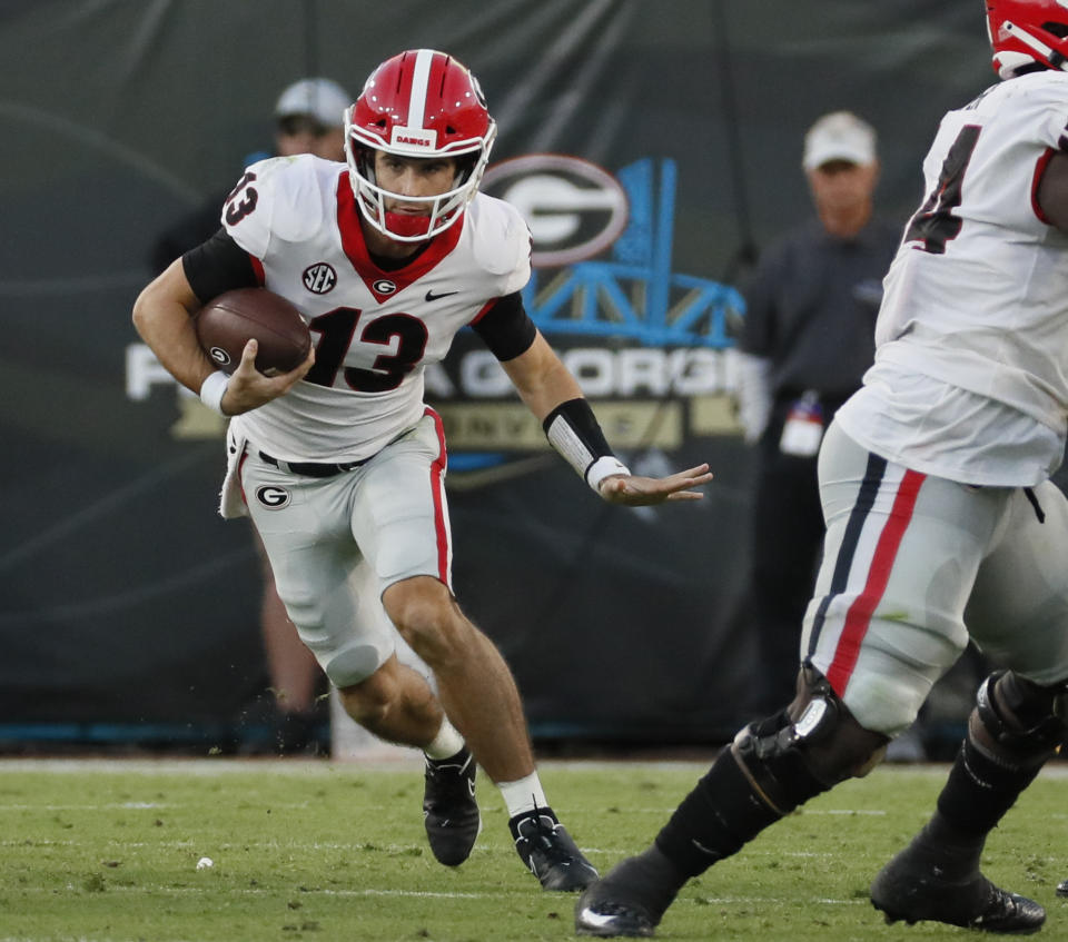 Georgia Bulldogs quarterback Stetson Bennett (13) scrambles for a first down during the second half of the annual NCCA Georgia vs Florida game at TIAA Bank Field in Jacksonville, Oct. 30, 2021. Georgia won 34-7. (Bob Andres/Atlanta Journal-Constitution via AP)