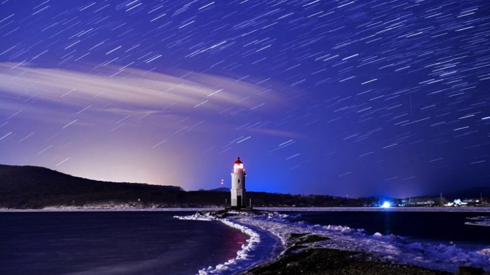 La lluvia de meteoritos Géminis durante su pico, en el cielo nocturno sobre el Faro Tokarevsky en el Cabo Egersheld en la Isla Russky en el Mar de Japón, diciembre de 2017.