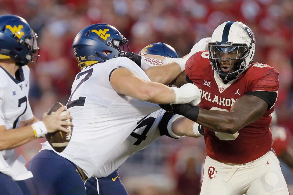 West Virginia's Doug Nester, left, tries to keep OU's Perrion Winfrey from getting to the quarterback.