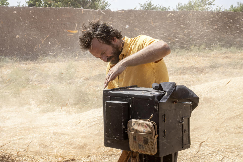 Rodrigo Abd, fotógrafo de The Associated Press, capta una imagen en un campo de trigo con una cámara de caja de madera el sábado 3 de junio de 2023, en Herat, Afganistán. (AP Foto/Ebrahim Noroozi)