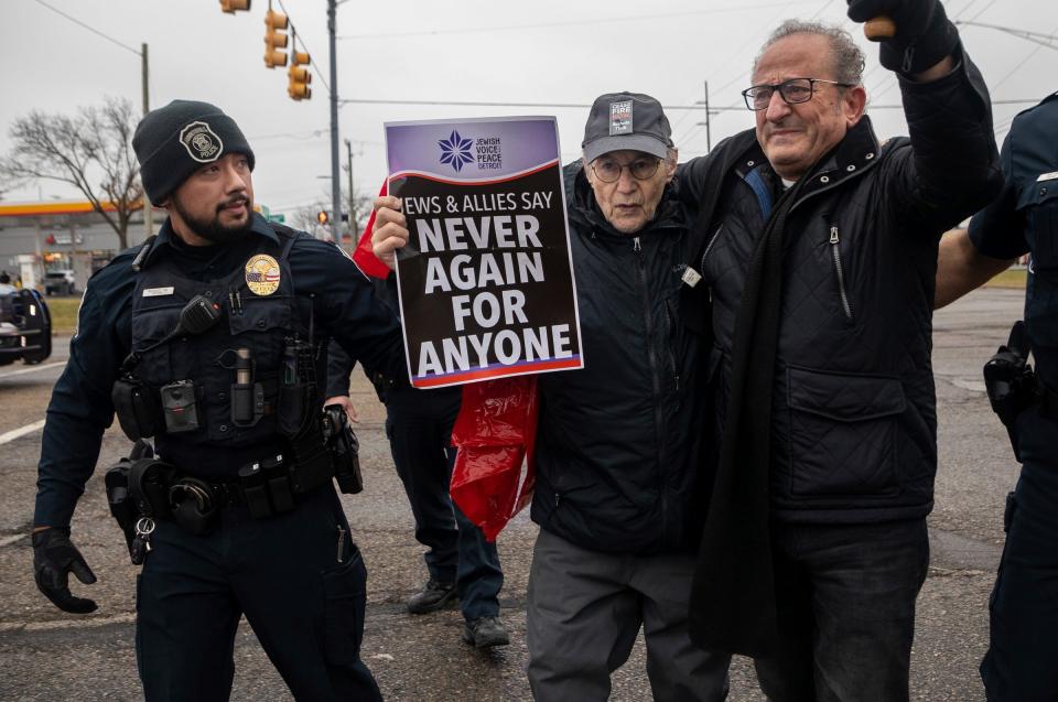 Holocaust survivor Rene Lichtman holds a sign saying, "Never Again for Anyone," as he and Nabil Sater march in Farmington Hills, Mich., on Dec. 22, 2023. The protesters, calling for a cease-fire in Gaza, temporarily blocked traffic and police escorted them back to the sidewalk.