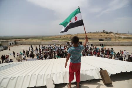 A boy holds the Free Syrian army flag during a protest calling for an end to the strikes and for Ankara to open the frontier at the Atmeh crossing on the Syrian-Turkish border, in Idlib governorate