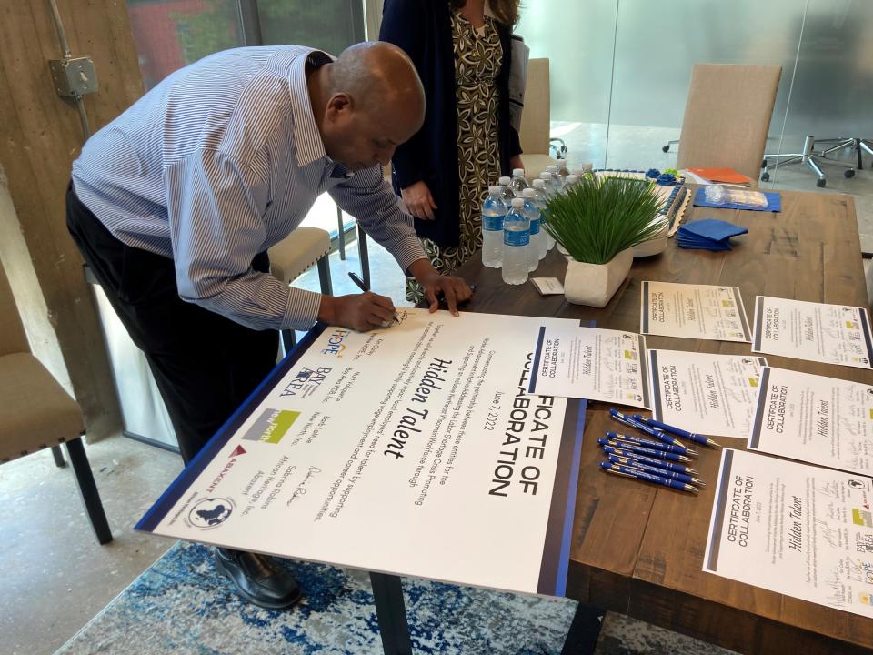 Adan Hurre, of COMSA, a Green Bay community services agency that works with with immigrants and refugees, signs a certificate pledging to collaborate with other community resource groups on Hidden Talent initiatives to help expand access to job training and support services in historically underserved populations.