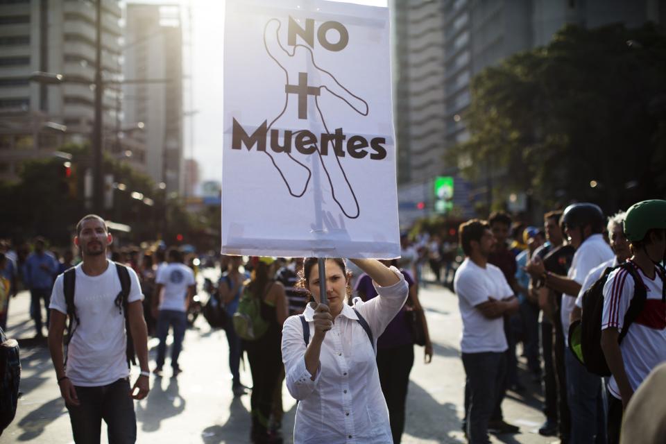 A woman holds a sign that reads in Spanish "No more deaths" at an opposition protest in Caracas, Venezuela, Wednesday, Feb. 19, 2014. The opposition is protesting the Tuesday detention of thier leader Leopoldo Lopez, as well as rampant crime, shortages of consumer goods and an inflation rate of more than 50 percent. (AP Photo/Rodrigo Abd)