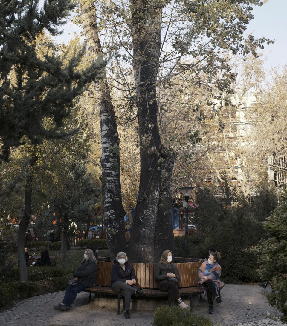 Women wearing masks to help protect against the spread of coronavirus, rest in a public garden, in Ankara, Turkey, Monday, Nov. 30, 2020. Turkey's President Recep Tayyip Erdogan has announced Monday the most widespread lockdown so far amid a surge in COVID-19 infections, extending curfews to weeknights and full lockdowns over weekends.(AP Photo/Burhan Ozbilici)