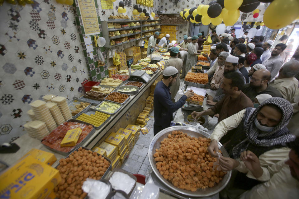 People buy traditional sweets in preparation for the upcoming Eid al-Fitr celebrations, at a shop, in Peshawar, Pakistan, Thursday, April 20, 2023. Eid al-Fitr marks the end of the Islamic holy month of Ramadan. (AP Photo/Muhammad Sajjad)