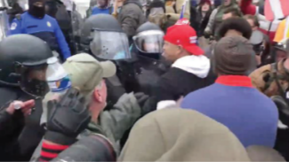 Ryan Stephen Samsel of Bucks County is shown here in the red cap at the U.S. Capitol, allegedly confronting police. One was thrown to the ground and blacked out. Samsel was arrested Jan. 30 on several charges.