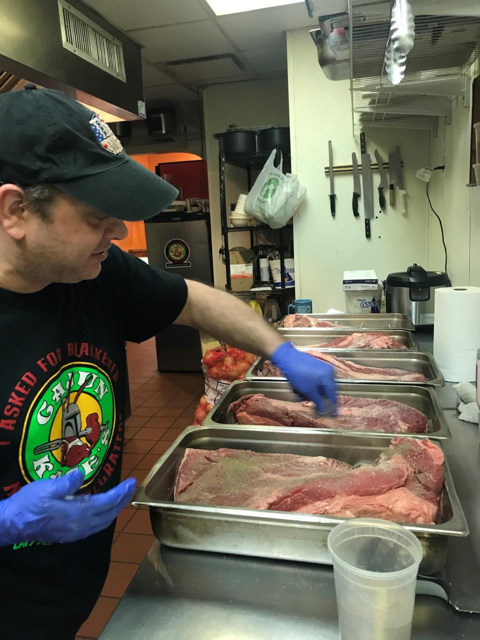 Don Applebaum, who owns Cajun Kate's on Philadelphia Pike near Bellefonte with his wife Kate, seasons pans of brisket in the kitchen of the restaurant. Applebaum regularly posts his specials in the Delaware takeout Facebook group.