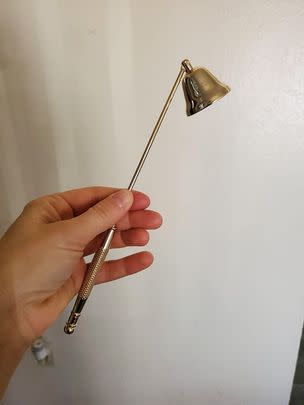 A gold candle snuffer that's beautiful, functional and a little extra all at the same time