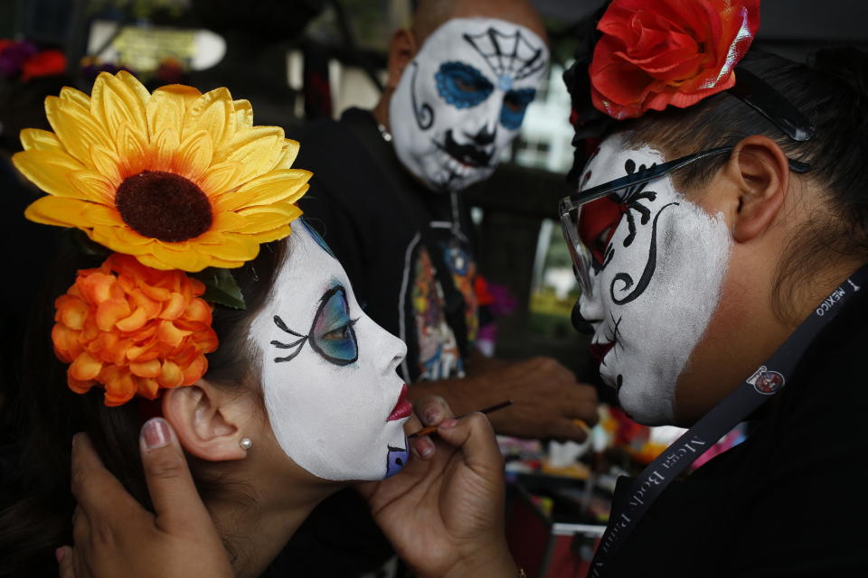 Ximena Bobadilla Ortiz, left, gets her face painted by Belen Marquez before the Catrinas parade down Mexico City's iconic Reforma avenue during Day of the Dead celebrations, Saturday, Oct. 26, 2019. (AP Photo/Ginnette Riquelme)