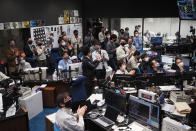 In this photo provided by the Japan Aerospace Exploration Agency (JAXA), Hayabusa2 project members react as they watch over the live streaming about the fireball phase of the re-entry capsule at a control room of JAXA's Sagamihara Campus in Sagamihara, near Tokyo, early Sunday, Dec. 6, 2020. A Japanese capsule carrying the first samples of asteroid subsurface shot across the night atmosphere early Sunday before successfully landing in the remote Australian Outback, completing a mission to provide clues to the origin of the solar system and life on Earth. (JAXA via AP)
