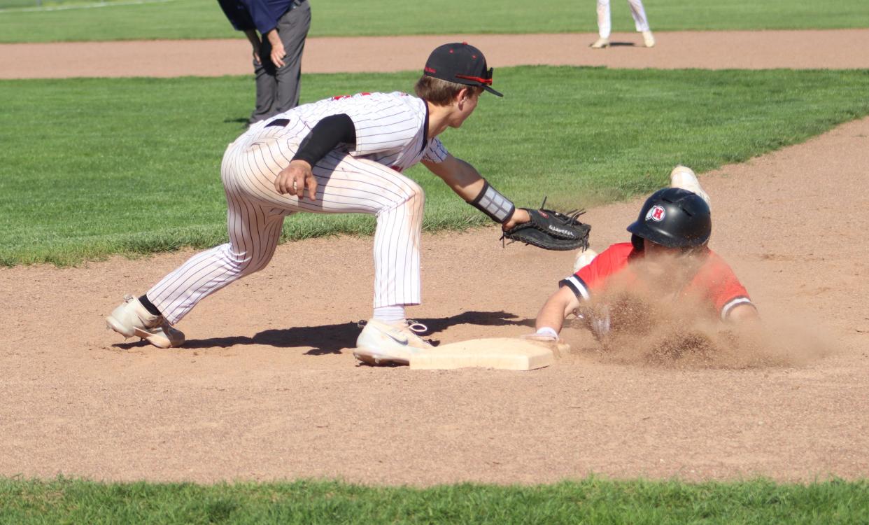 New Boston Huron's Jakob Furkas dives back into first base during a 10-7 win over Milan on Wednesday, May 1, 2024.