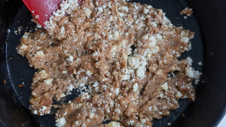 refried beans and questo fresco in a cast iron skillet