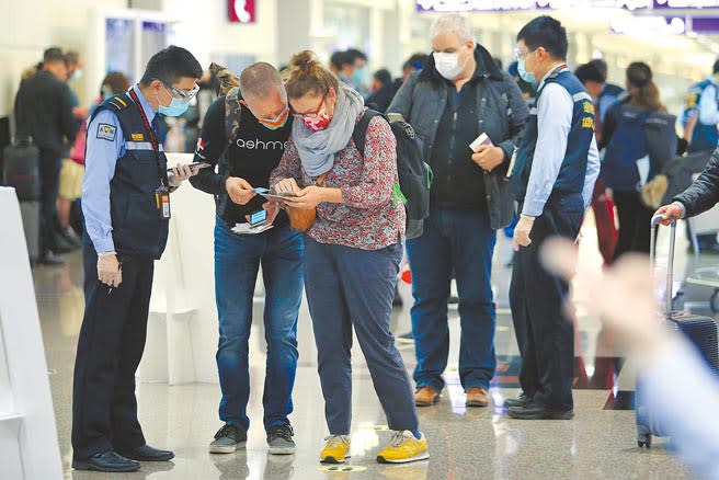 桃園機場第二航廈準備入境申報健康聲明與檢疫資料的外國旅客。（陳麒全攝）