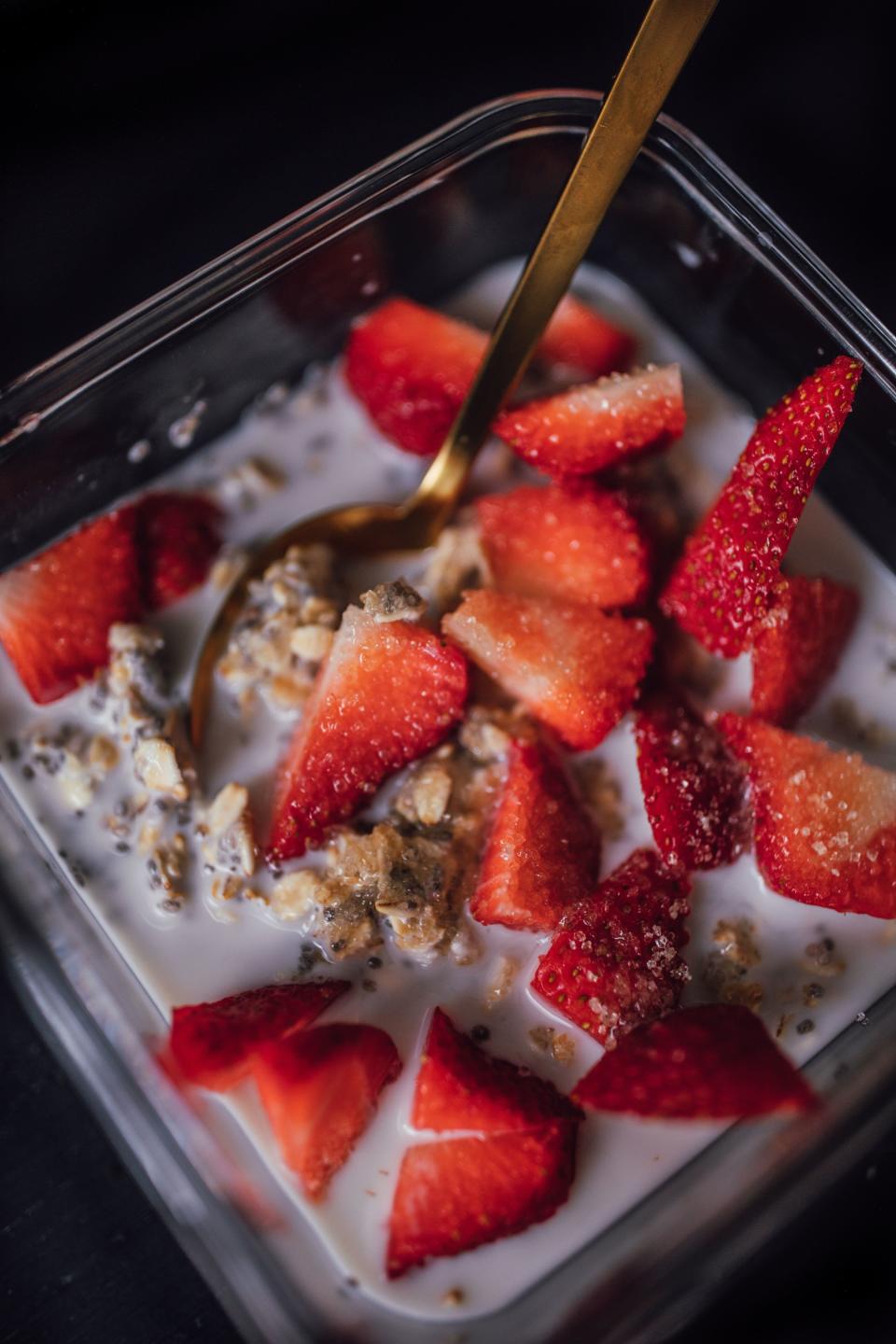 dipping spoon into a single-serve container of oatmeal with milk and fruit