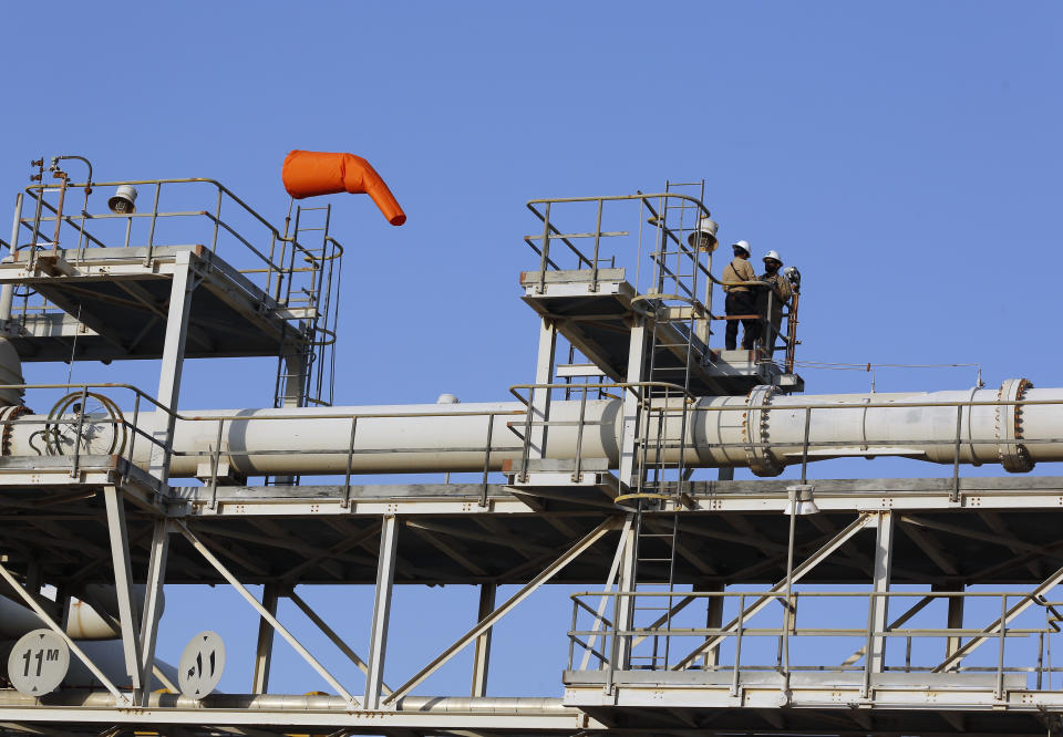 FILE - In this Friday, Sept. 20, 2019 file photo, workers seen in Aramco's oil separator at processing facility in Abqaiq, near Dammam in the Kingdom's Eastern Province. Saudi Arabia's state-owned oil company Aramco on Thursday, Dec. 5, 2019, set a share price for its IPO — expected to be the biggest ever — that puts the value of the company at $1.7 trillion, more than Apple or Microsoft. (AP Photo/Amr Nabil, File)