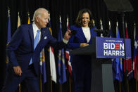 Democratic presidential candidate former Vice President Joe Biden retrieves his face mask from the podium as his running mate Sen. Kamala Harris, D-Calif., prepares to speak at a campaign event at Alexis Dupont High School in Wilmington, Del., Wednesday, Aug. 12, 2020. (AP Photo/Carolyn Kaster)