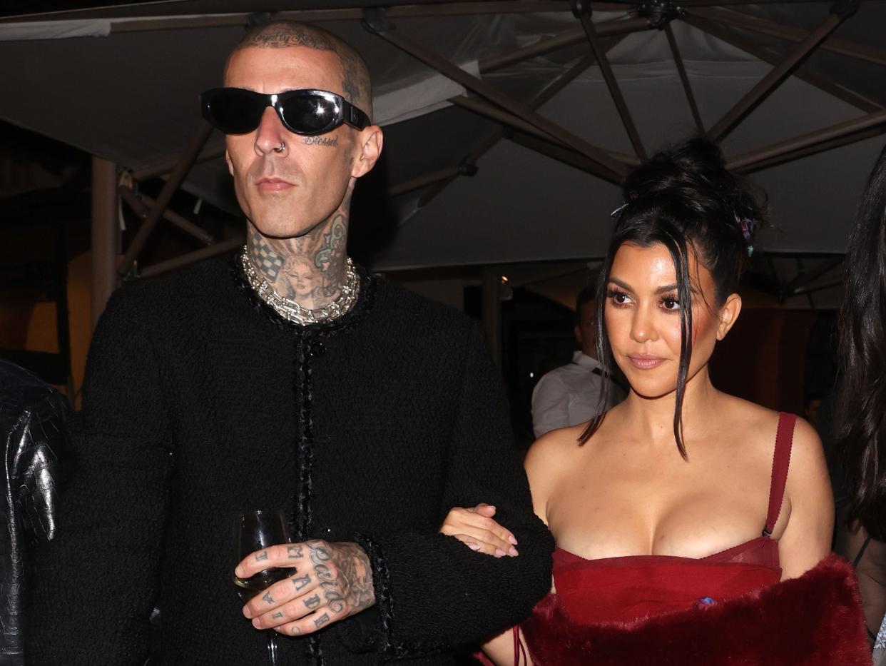 Travis Barker in all black and Kourtney Kardashian in all red