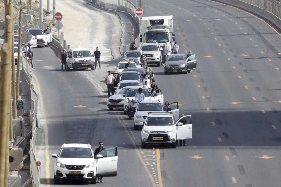 Israelis stand next to their cars as sirens mark a nationwide moment of silence in remembrance of the 6 million Jewish victims of the Holocaust, in Tel Aviv, Israel, Thursday, April 8, 2021. (AP Photo/Sebastian Scheiner)