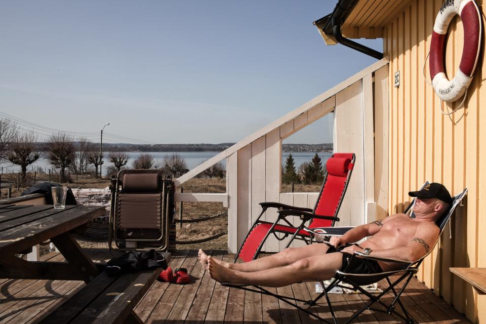 BASTOY ISLAND, HORTEN, NORWAY - APRIL 11:  An inmate which gave the fake name of Niels, 36-years-old sentenced to sixtheen years and a half for murder and narcotics related crime is seen sun bathing in front of the wooden cottage where he lives in Bastoy Prison on April 11, 2011 in Bastoy Island, Horten, Norway. Bastoy Prison is a minimum security prison located on Bastoy Island, Norway, about 75 kilometers (46 mi) south of Oslo. The facility is located on a 2.6 square kilometer (1 sq mi) island and hosts 115 inmates. Arne Kvernvik Nilsen, governor of the prison, leads a staff of about 70 prison employees. Of this staff, only five employees remain on the island overnight.  Once a prison colony for young boys, the facility now is trying to become 'the first eco-human prison in the world.' Inmates are housed in wooden cottages and work the prison farm. During their free time, inmates have access to horseback riding, fishing, tennis, and cross-country skiing. (Photo by Marco Di Lauro/Reportage by Getty Images)