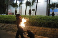 A protester's back catches fire after attempting to throw a Molotov cocktail during a protest in Hong Kong on Saturday, Sept. 21, 2019. Protesters in Hong Kong burned a Chinese flag and police fired pepper spray Saturday in renewed clashes over grievances by the anti-government demonstrators. (AP Photo/Kin Cheung)