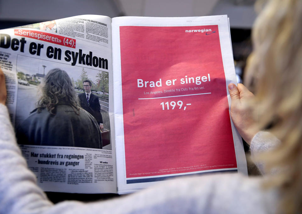 A woman holds a newspaper with an advert for Norwegian Air Shuttle in Oslo