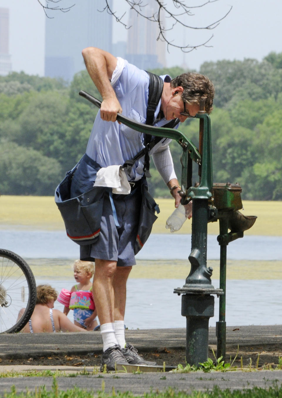 Postal carrier Paul Schimke takes a break to pump water into his bottle at an old-fashioned pump along Lake Harriet Friday, July 6, 2012 in Minneapolis where temperatures reached into the upper 90's for another day during the heat wave. The National Weather Service said the record-breaking heat that has baked the nation’s midsection for several days was slowly moving into the mid-Atlantic states and Northeast. Excessive-heat warnings remained in place Friday for all of Iowa, Indiana and Illinois as well as much of Wisconsin, Michigan, Missouri, Ohio and Kentucky. (AP Photo/Jim Mone)