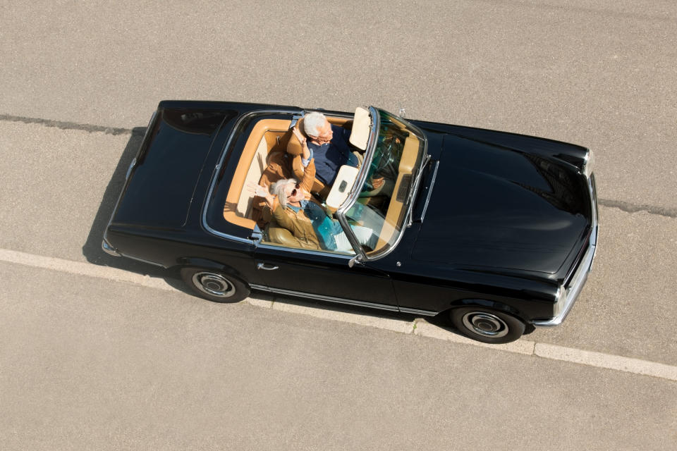 A couple are riding in a convertible with the top down