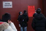 People look at a notice at the gate of the Lama Temple saying that the temple is closed for the safety concern following the outbreak of a new coronavirus, in Beijing