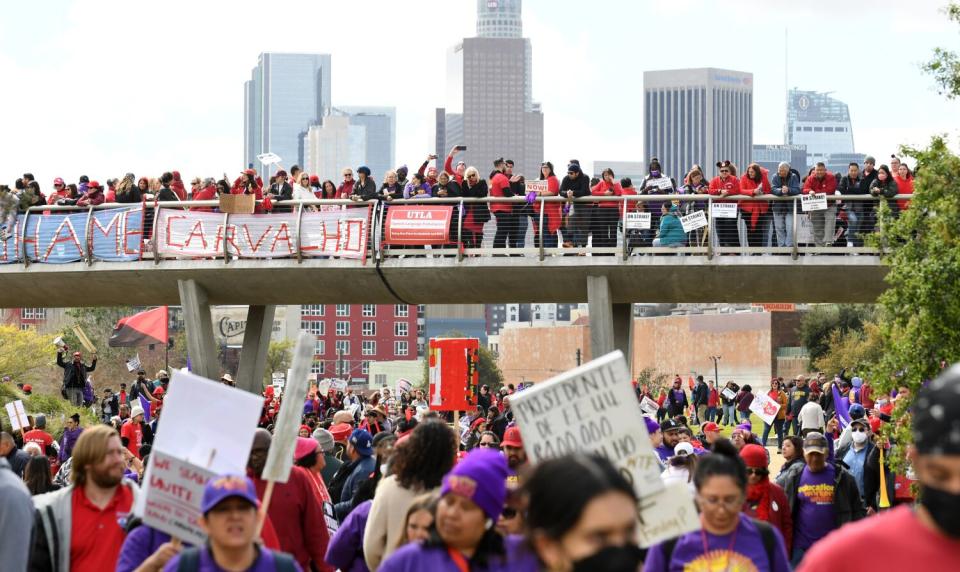 Picketers carry signs with the downtown L.A. skyline in the background.