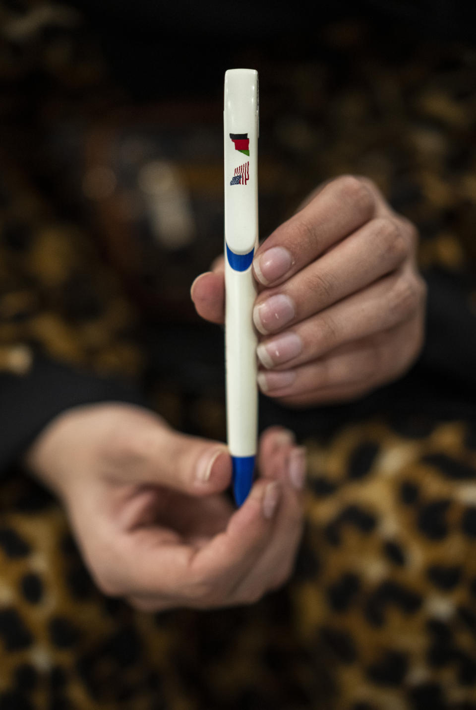 Meena, a 21-year-old student of the American University of Afghanistan holds a school pen with the U.S. and Afghanistan flag inside the Islamabad airport, Pakistan, Saturday, Oct. 2, 2021. Along with other students, Meena left Afghanistan without her family. She took the pen with her because it has the flag of her country on it, the one now replaced in Afghanistan by the Taliban flag. “We just burned our dreams ... we are just broken people.” (AP Photo/Bernat Armangue)