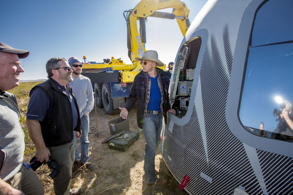 In this undated photo made available by Blue Origin, Jeff Bezos, center, and others inspect Crew Capsule 2.0 after touchdown in West Texas. When Blue Origin launches people into space for the first time, Bezos will be on board. No test pilots or flight engineers for the Tuesday, July 20, 2021 debut flight from West Texas - just Bezos, his brother, an 82-year-old aviation pioneer and a teenager. (Blue Origin via AP)