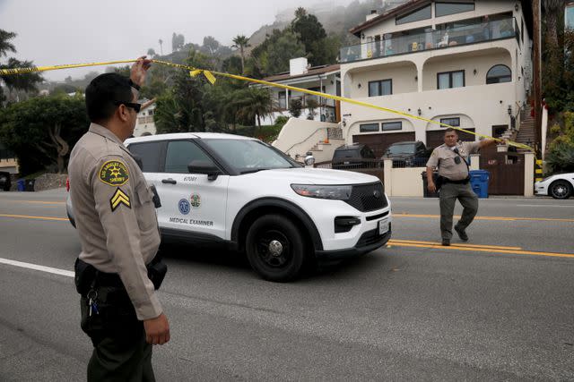 <p>Genaro Molina/Los Angeles Times via Getty</p> Sheriff deputies lift the yellow tape for a Medical Examiner car leaving the scene where four women were killed in a multi-vehicle crash in Malibu on October 18, 2023.
