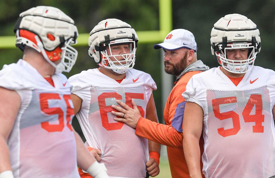 Clemson offensive lineman Will Putnam (56), left, offensive lineman Chapman Pendergrass (65) offensive line coach Thomas Austin, and offensive lineman Mason Trotter (54) during practice at the Poe Indoor Facility in Clemson Monday, August 8, 2022. 