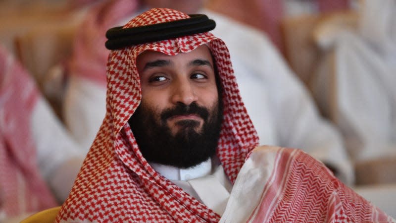 A man in a keffiyeh smirks at something off-camera.