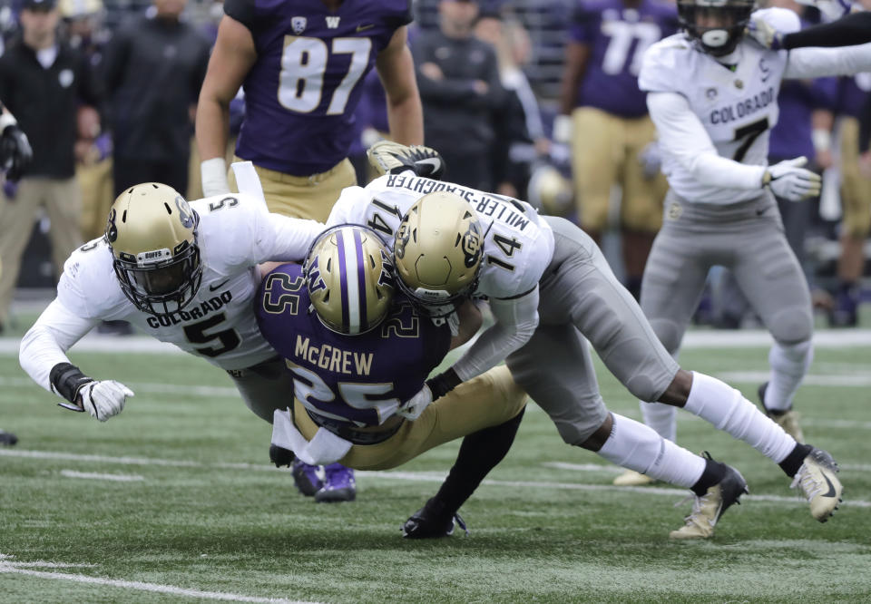 Washington tailback Sean McGrew (25) is tackled by Colorado's Davion Taylor, left, and Chris Miller-Slaughter (14) during the first half of an NCAA college football game, Saturday, Oct. 20, 2018, in Seattle. (AP Photo/Ted S. Warren)