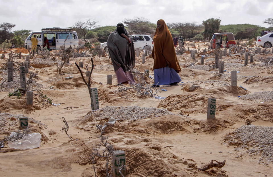 In this photo taken Wednesday, May, 13, 2020, women walk past graves at a cemetery in Mogadishu, Somalia, following the burial of a man who died of coronavirus. Years of conflict, instability and poverty have left Somalia ill-equipped to handle a health crisis like the coronavirus pandemic. It’s uncertain how many cases of COVID-19 are in Somalia. (AP Photo/Farah Abdi Warsameh)