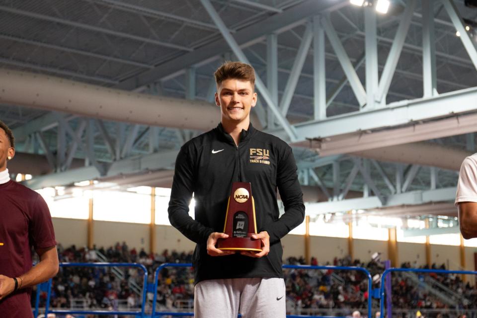 Florida State's Trey Cunningham smiles while holding his 60-meter hurdle national championship trophy.